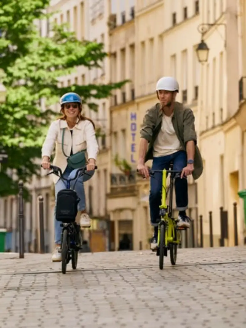Zwei JobRadler:innen fahren auf ihren Falträdern von Brompton durch die Stadt