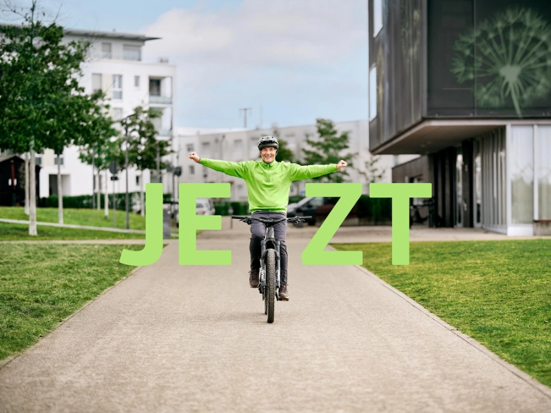 JobRadler fährt strahlend auf seinem Fahrrad mit gestreckten Armen mit Schriftzug "Jetzt" JobRadler fährt strahlend auf seinem Fahrrad mit gestreckten Armen mit Schriftzug "Jetzt"