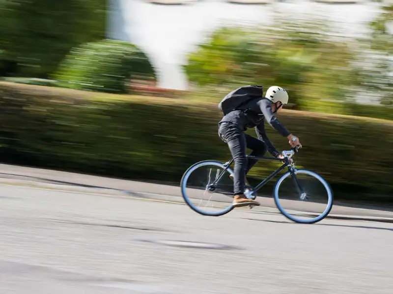 Ein Radfahrer mit Helm fährt schnell eine Straße herunter