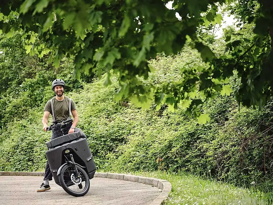 Ein JobRadler auf dem Lastenrad steht in einer Kurve Ein JobRadler auf dem Lastenrad steht in einer Kurve