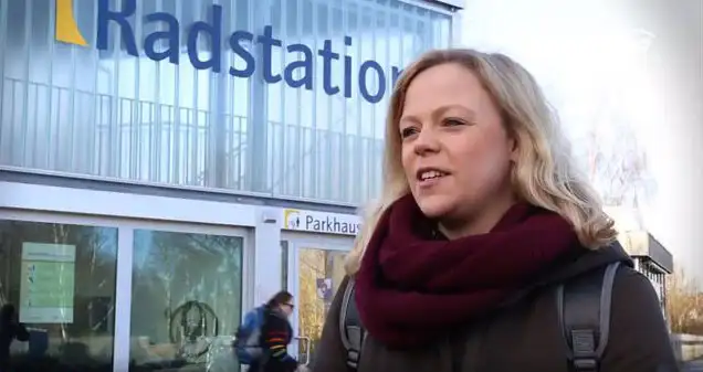Maraike Kahlstorf von Rewe steht vor einem Gebäude mit der Aufschrift "Radstation". Sie trägt einen roten Wollschal