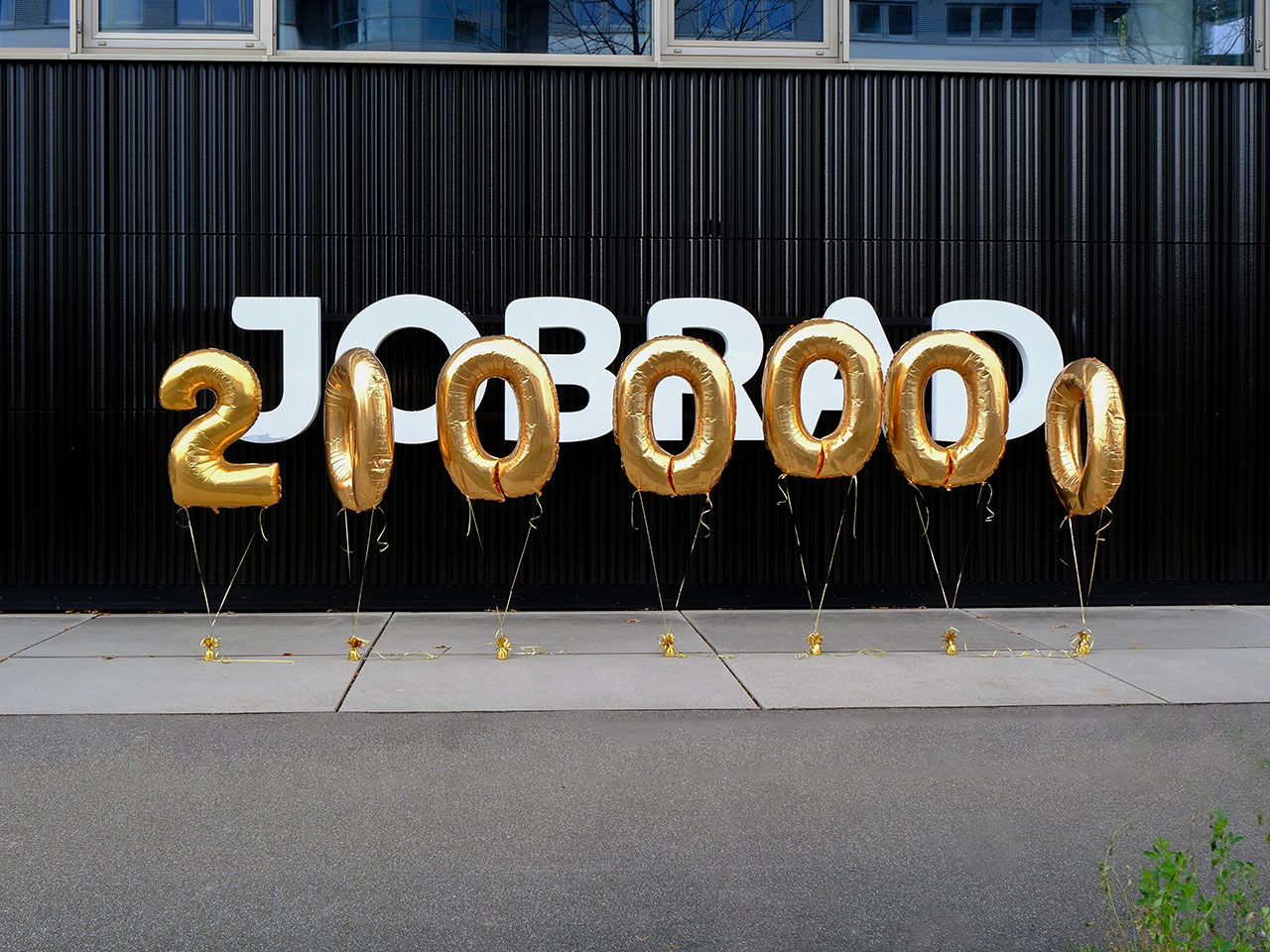 gelbe Luftballons bilden 2 Millionen und fliegen vor dem JobRad-Logo gelbe Luftballons bilden 2 Millionen und fliegen vor dem JobRad-Logo