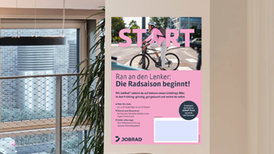 Das Poster "Die Radsaison beginnt!" hängt an einer Bürowand