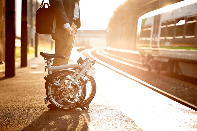Businessmensch mit Faltrad wartet auf den Zug
