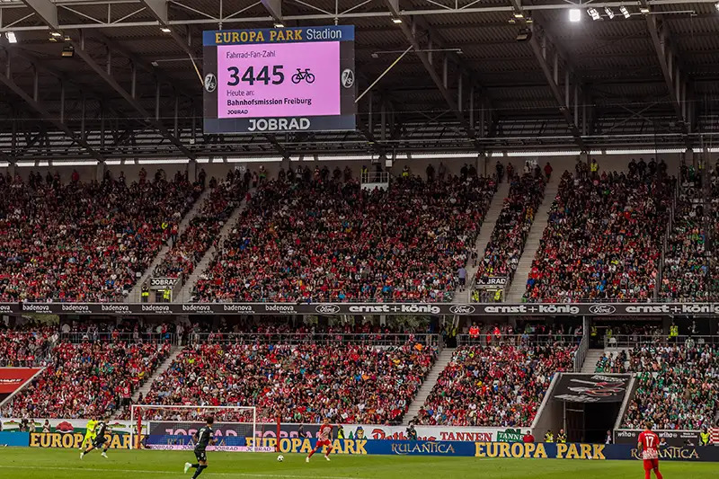 Das Bild zeigt die Anzeigetafel im Europa-Park-Stadion mit der aktuellen Fan-Zahl. Die Spende geht an die Bahnhofsmission Freiburg